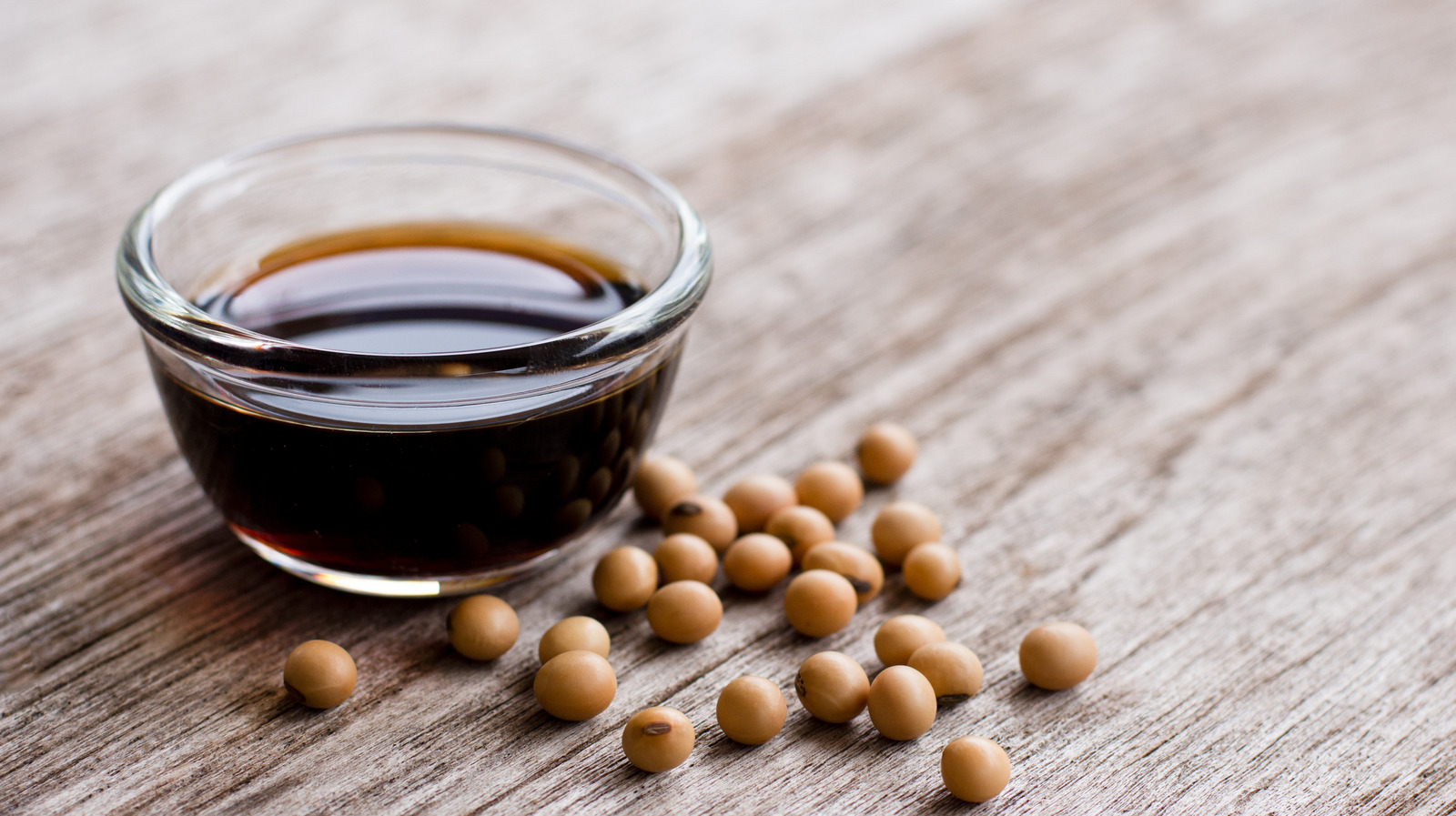 Soy,Sauce,In,Glass,Bowl,With,Soybeans,Isolated,On,Wooden